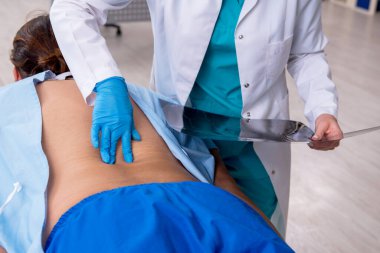 Genç sırtı yaralı bir adam, kadın doktor masörünü ziyaret ediyor.