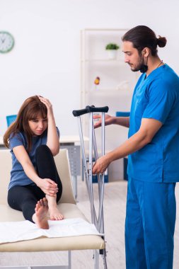 Erkek doktor travmatoloğu ziyaret eden yaralı bir kadın.