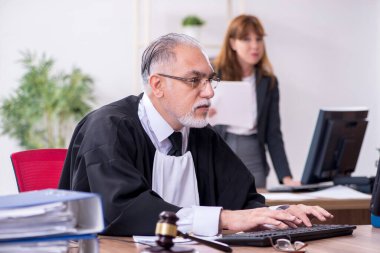 Yaşlı erkek yargıç ve genç sekreteri ofiste.