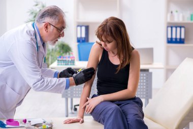 Genç kadın yaşlı erkek doktoru ziyaret ediyor.