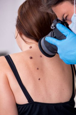 Genç bir kadın erkek doktor dermatoloğunu ziyaret ediyor.