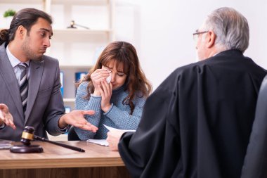 Yargıç ve avukatla birlikte adliyede genç bir kadın.
