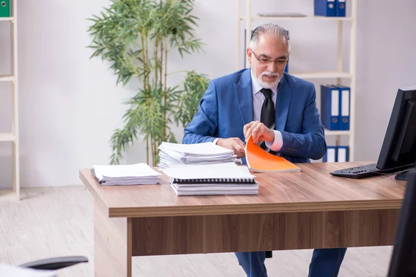 Alte männliche Mitarbeiter und exzessive Arbeit im Büro — Stockfoto