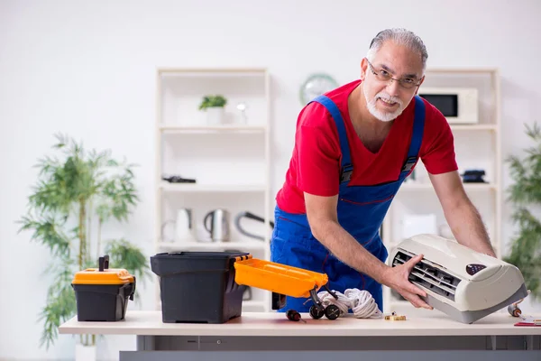 Viejo contratista reparando aire acondicionado en interiores — Foto de Stock