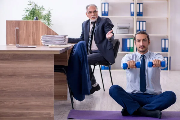 Two employees doing physical exercises at workplace — Stock Photo, Image