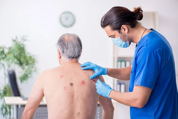 Starý muž návštěva mladý lékař dermatolog — Stock fotografie