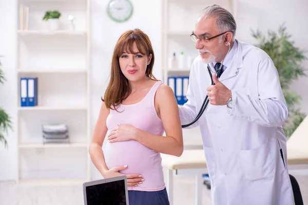 Jonge zwangere vrouw bezoekt oude mannelijke arts gynaecoloog — Stockfoto