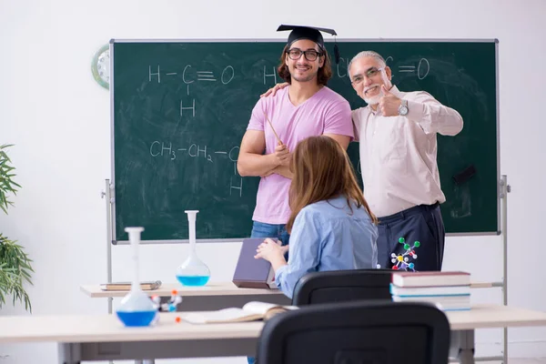 Old chemist teacher and two students in the classroom