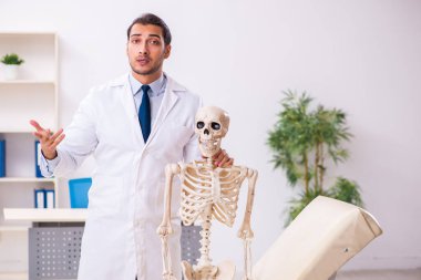 İskeleti olan genç erkek doktor.