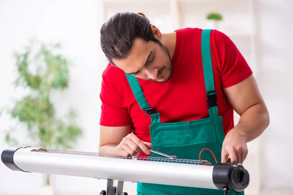 Jovem empreiteiro masculino reparando aquecedor dentro de casa — Fotografia de Stock