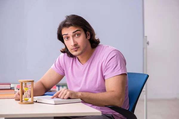Jovem estudante do sexo masculino em sala de aula no conceito de gestão de tempo — Fotografia de Stock