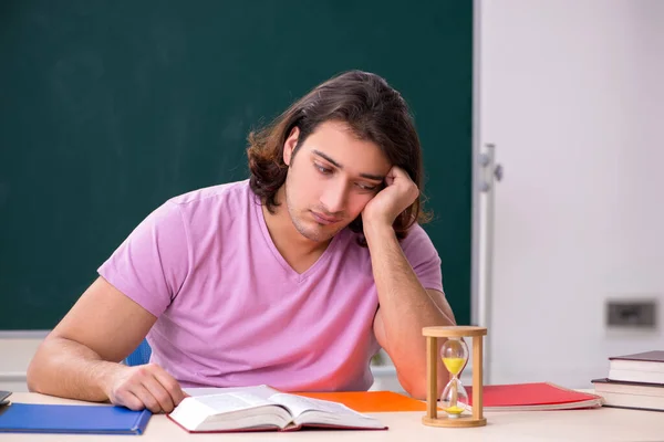 Young male student in the classroom at time management concept — Stock Photo, Image