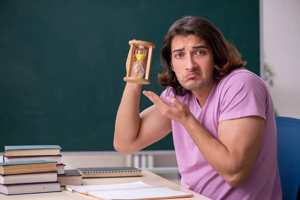 Jonge mannelijke student in het klaslokaal op tijdmanagementconcept — Stockfoto