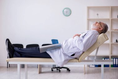 Klinikte çalışan yaşlı erkek doktor.