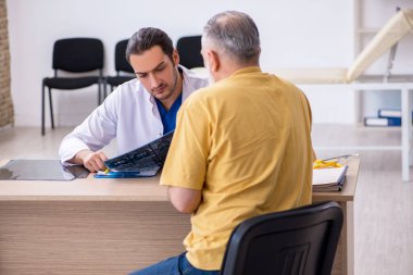 Yaşlı hasta, genç erkek doktor radyolojisti ziyaret ediyor.