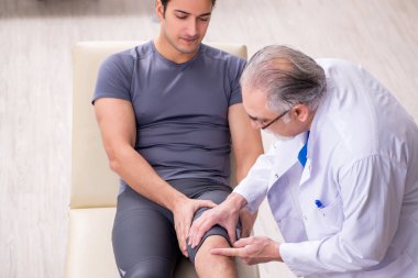 Genç erkek hasta yaşlı doktor travmatoloğu ziyaret ediyor.