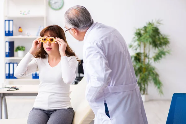 Jonge vrouw bezoekt oude mannelijke arts oogarts — Stockfoto