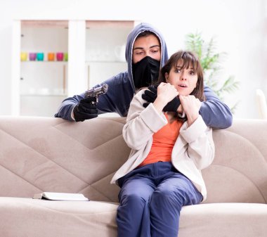 Silahlı bir adam evde genç bir kadına saldırıyor.