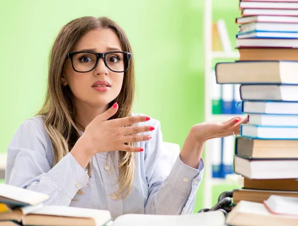 Jovem estudante se preparando para exames com muitos livros — Fotografia de Stock