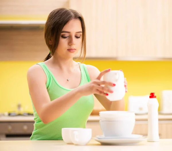 Mujer joven limpiando y lavando platos en la cocina — Foto de Stock