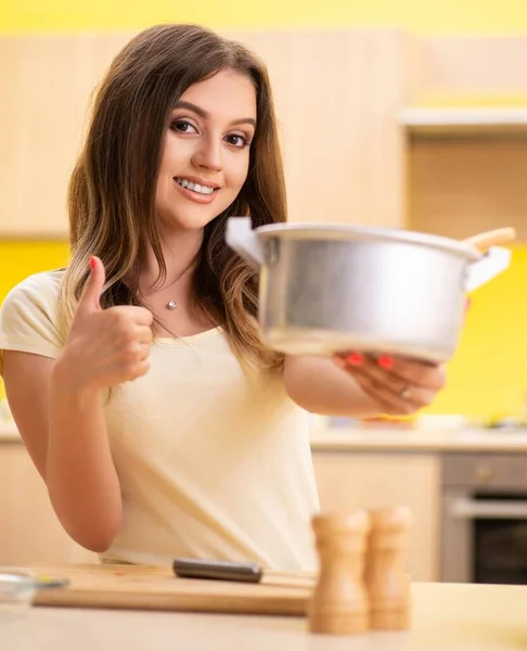 Młoda kobieta gotowanie zupy w kuchni w domu — Zdjęcie stockowe