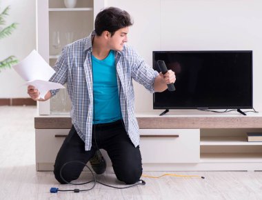 Bozuk televizyonu tamir etmeye çalışan adam