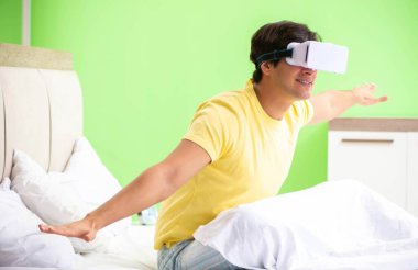 Yatak odasında sanal gözlüklü genç adam.