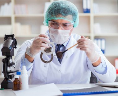 Kriminolog polis kimyageri suç delillerine bakıyor.