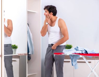 Genç adam yatak odasında ütü yapıyor.