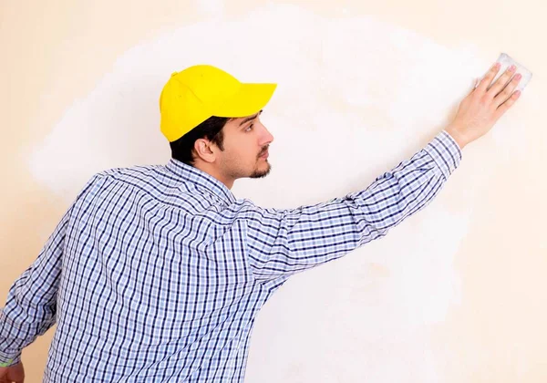 Ung entreprenör sandning vägg ner med sandpapper — Stockfoto