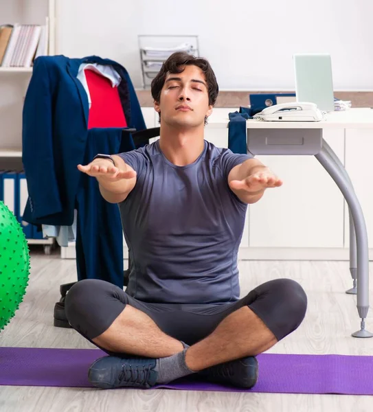 Ofiste egzersiz yapan genç bir erkek.