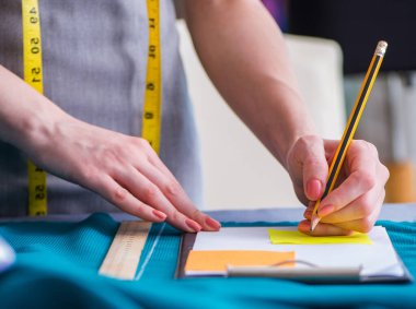 Kadın terzi dikiş dikmek için dikiş dikiyor.