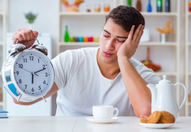 Çalar saati olan bir adam kahvaltıda uyuyakalıyor.