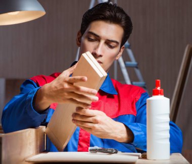 Genç adam ahşap parçaları diy konseptinde yapıştırıyor.