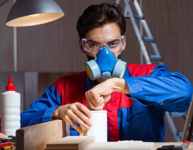 Genç adam ahşap parçaları diy konseptinde yapıştırıyor.