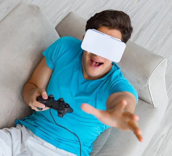 Hombre joven con gafas VR relajándose en sofá —  Fotos de Stock