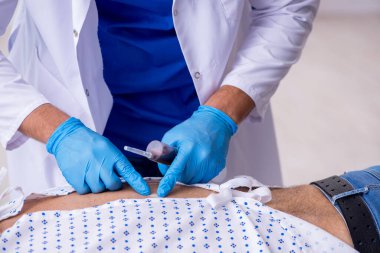 Yaşlı adam genç erkek stajyer doktoru ziyaret ediyor.