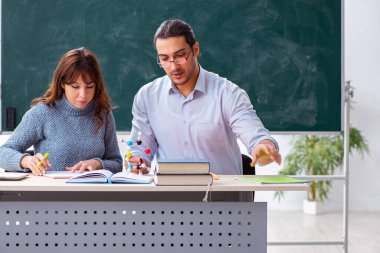 Genç bayan öğrenci ve erkek öğretmen sınıfta.