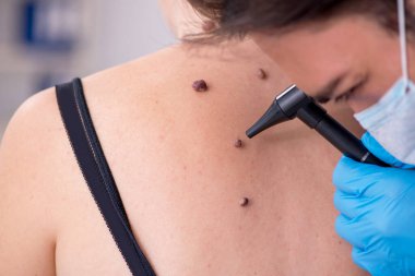 Genç bir kadın erkek doktor dermatoloğunu ziyaret ediyor.