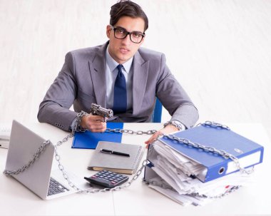 Ofis masasına zincirlenmiş meşgul bir çalışan.