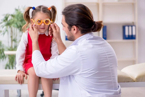 Menina pequena visitando jovem médico oculista masculino — Fotografia de Stock