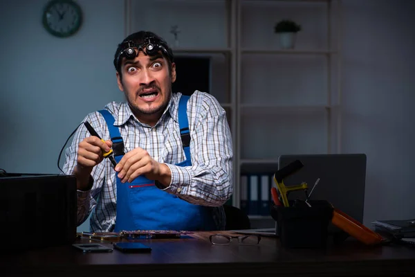 Young male technician repairing computer in workshop at night — Stock Photo, Image