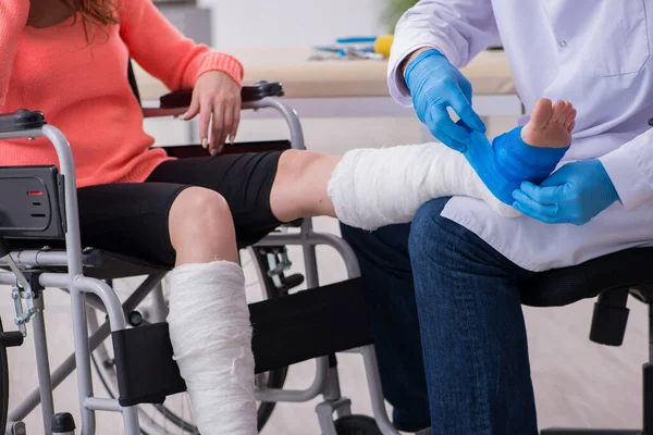 Fiatal láb sérült nő látogató idős orvos traumatológus — Stock Fotó