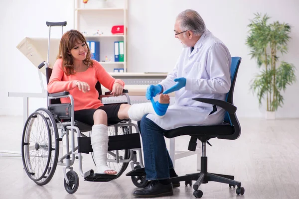 Unga ben skadad kvinna besöker gamla läkare traumatolog — Stockfoto