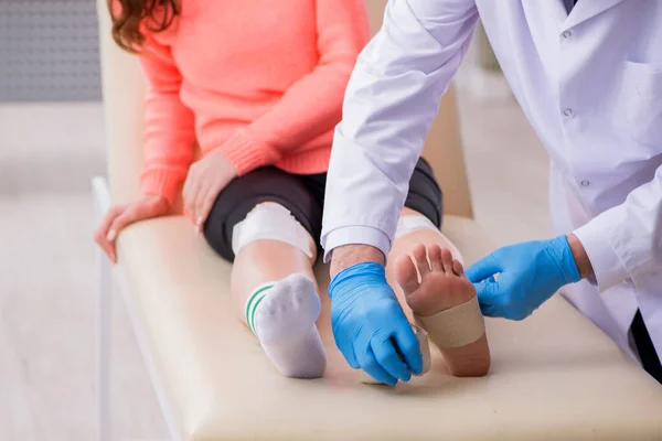 Mladý noha zranění žena hostující starý lékař traumatolog — Stock fotografie
