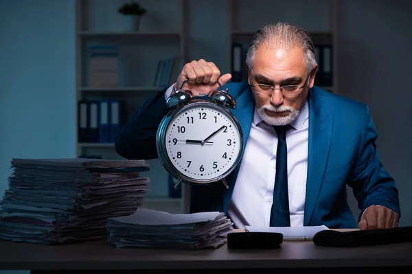 Oude mannelijke werknemer die laat op kantoor werkt — Stockfoto