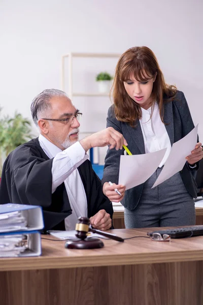 Oude mannelijke rechter en zijn jonge secretaresse op kantoor — Stockfoto