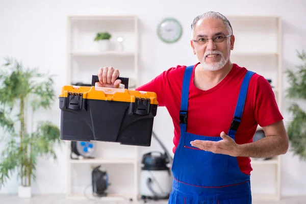 Old male contractor repairing household devices indoors