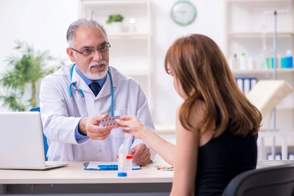 Jovem mulher visitando velho médico masculino — Fotografia de Stock