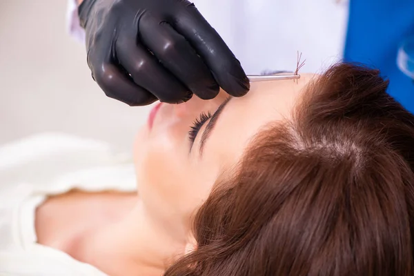 Молодая женщина, посещающая мужчину-косметолога в деле о трансплантации волос — стоковое фото